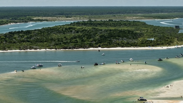 Aerial view of Matanzas Inlet featuring sandbars turquoise water and numerous boats anchored near the shore surrounded by lush coastal vegetation in St. Johns County Florida United States. Aerial view of Matanzas Inlet featuring sandbars turquoise water and numerous boats anchored near the shore surrounded by lush coastal vegetation in St. Johns County Florida United States.