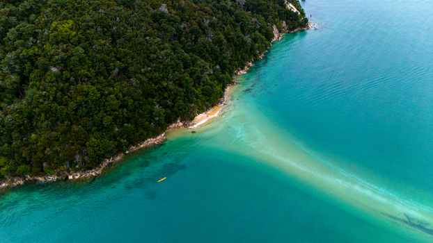 Aerial view of a lush green headland meets the turquoise waters of a bay creating a stunning contrast of colors and textures Abel Tasman National Park Tasman Region New Zealand. Aerial view of a lush green headland meets the turquoise waters of a bay creating a stunning contrast of colors and textures Abel Tasman National Park Tasman Region New Zealand.