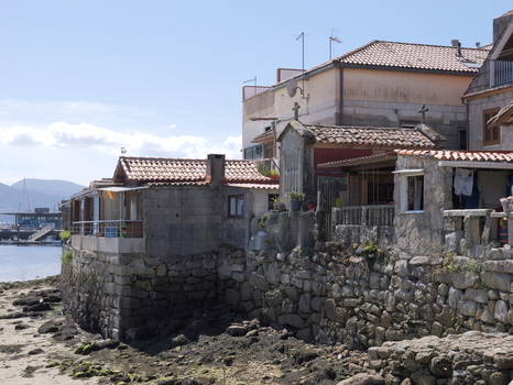 View of traditional stone houses and historic granaries along the rocky coastline in the coastal village of Combarro Pontevedra Spain.