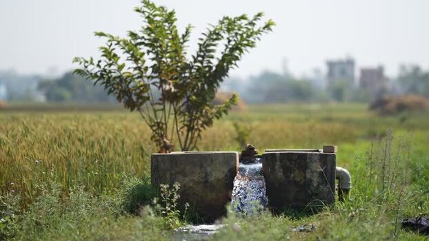 View of water flowing from an irrigation pump in a field Nepal.