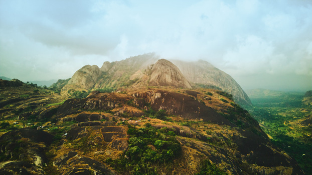 Aerial view of the ancient and rocky Idanre Hills rising majestically shrouded in mist a timeless landscape of earthy browns and verdant greens Idanre Ondo Nigeria. Aerial view of the ancient and rocky Idanre Hills rising majestically shrouded in mist a timeless landscape of earthy browns and verdant greens Idanre Ondo Nigeria.