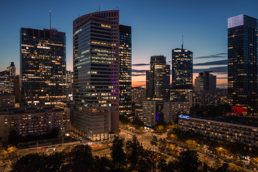 Warsaw Poland 10 September 2026 Aerial view of Q22 skyscraper at twilight in the business district with glowing office towers city streets and urban greenery.