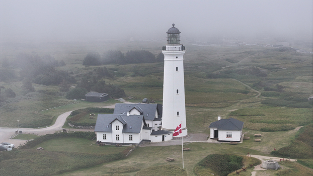 Aerial view of Hirtshals Fyr lighthouse standing amidst grassy dunes and foggy coastal landscape in Hirtshals Denmark. Aerial view of Hirtshals Fyr lighthouse standing amidst grassy dunes and foggy coastal landscape in Hirtshals Denmark.