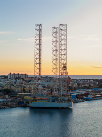 Aerial view of Uljanik Shipyard with a large jack up rig docked in the harbor surrounded by urban buildings and the calm sea at sunset in Pula Croatia. Aerial view of Uljanik Shipyard with a large jack up rig docked in the harbor surrounded by urban buildings and the calm sea at sunset in Pula Croatia.