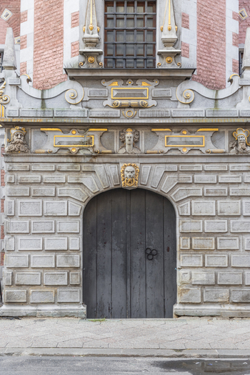 View of the ornate stone entrance and wooden door of the historic Great Armoury building with detailed carvings and brick facade in Gdansk Pomeranian Voivodeship Poland. View of the ornate stone entrance and wooden door of the historic Great Armoury building with detailed carvings and brick facade in Gdansk Pomeranian Voivodeship Poland.