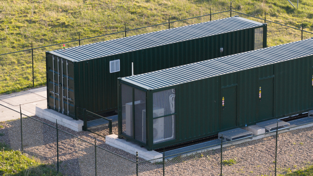Aerial view of Solar park Delfzijl featuring green industrial containers within a fenced enclosure on a grassy field in Farmsum Groningen Netherlands. Aerial view of Solar park Delfzijl featuring green industrial containers within a fenced enclosure on a grassy field in Farmsum Groningen Netherlands.