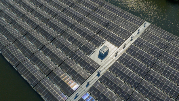 Aerial view of a large floating solar farm with rows of photovoltaic panels reflecting sunlight on a calm body of water in Zwolle Overijssel Netherlands. Aerial view of a large floating solar farm with rows of photovoltaic panels reflecting sunlight on a calm body of water in Zwolle Overijssel Netherlands.