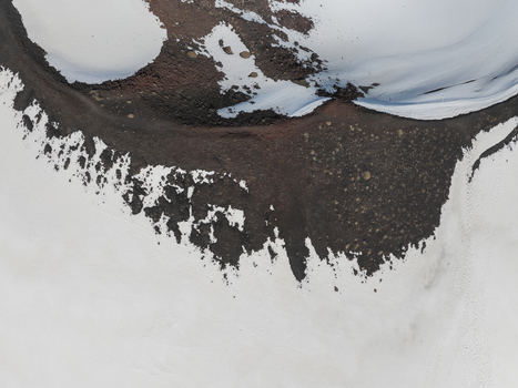 Aerial view of the south slope of Mount Etna showing the contrast between dark volcanic earth and white snow patches in Nicolosi Sicilia Italy. Aerial view of the south slope of Mount Etna showing the contrast between dark volcanic earth and white snow patches in Nicolosi Sicilia Italy.