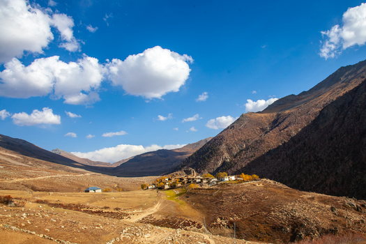 View of Deosai National Park featuring a small mountain village with stone houses nestled in an arid landscape under a bright blue sky in Astore Gilgit Pakistan. View of Deosai National Park featuring a small mountain village with stone houses nestled in an arid landscape under a bright blue sky in Astore Gilgit Pakistan.