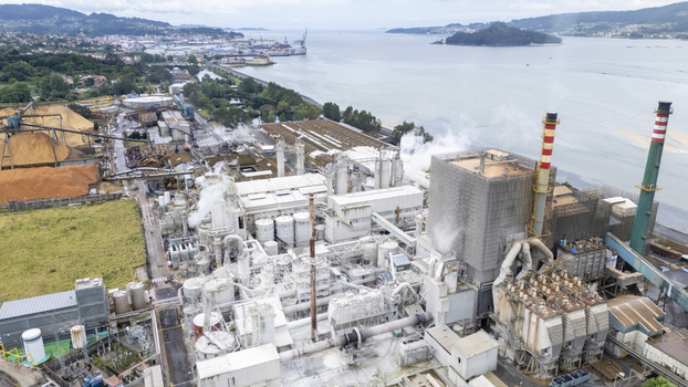 Aerial view of the Biofabrica de Ence pulp mill with industrial structures smoke rising from chimneys and wood chip piles along the coast in Pontevedra Pontevedra Spain. Aerial view of the Biofabrica de Ence pulp mill with industrial structures smoke rising from chimneys and wood chip piles along the coast in Pontevedra Pontevedra Spain.