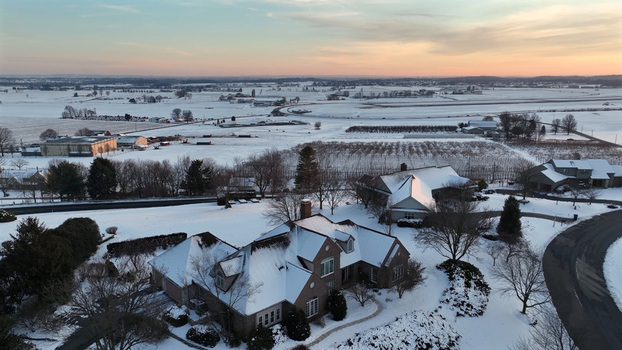 Aerial view of a residential area in Warwick Township covered in snow during a golden sunset featuring suburban homes and fields in Warwick Township Pennsylvania United States.