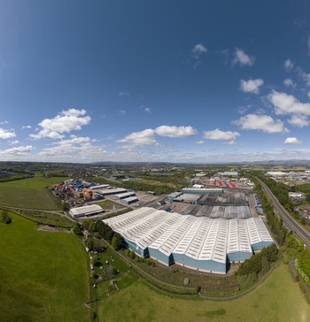 04 May 2026 Aerial view of large industrial warehouses and storage facilities surrounded by lush green fields and a highway under a bright blue sky with white clouds. 04 May 2026 Aerial view of large industrial warehouses and storage facilities surrounded by lush green fields and a highway under a bright blue sky with white clouds.