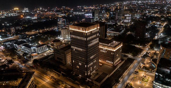 Aerial view of the illuminated Bank Square building at night surrounded by city lights and urban infrastructure in Accra Greater Accra Region Ghana.