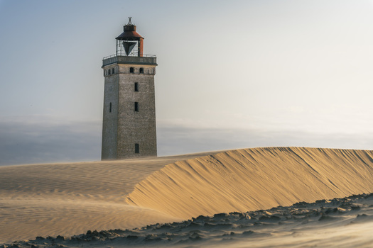 View of Rubjerg Knude lighthouse standing amidst shifting sand dunes under a clear sky in Lokken Denmark. View of Rubjerg Knude lighthouse standing amidst shifting sand dunes under a clear sky in Lokken Denmark.