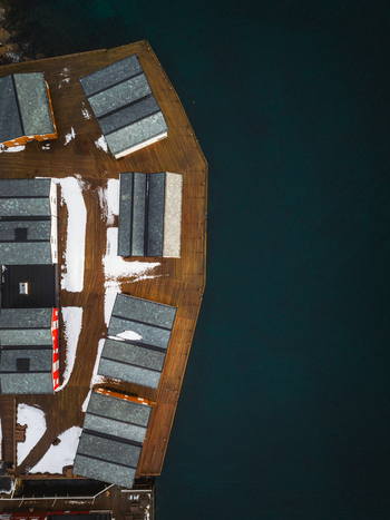 Aerial view of weathered wooden structures meet the dark still waters a stark contrast under a muted sky Henningsv&aelig;r Nordland Norway.