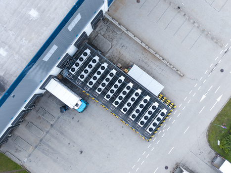 Aerial view of a logistics hub featuring a warehouse building with loading docks a parked truck and a row of industrial HVAC units on the roof in Skawina Lesser Poland Voivode Poland. Aerial view of a logistics hub featuring a warehouse building with loading docks a parked truck and a row of industrial HVAC units on the roof in Skawina Lesser Poland Voivode Poland.