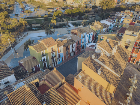 Aerial view of colorful traditional houses with tiled rooftops and palm trees lining a quiet street in the historic center La Vila Joiosa Valencian Community Spain. Aerial view of colorful traditional houses with tiled rooftops and palm trees lining a quiet street in the historic center La Vila Joiosa Valencian Community Spain.