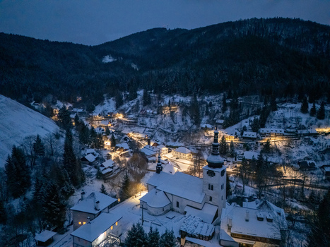Aerial view of the historic village of Spania Dolina with its illuminated church and snow covered rooftops nestled in a dark valley at night Spania Dolina Banska Bystrica Region Slovakia. Aerial view of the historic village of Spania Dolina with its illuminated church and snow covered rooftops nestled in a dark valley at night Spania Dolina Banska Bystrica Region Slovakia.