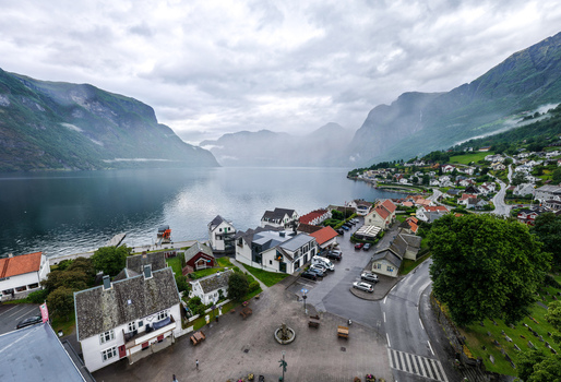 Aerial view of the village of Flam nestled along the Aurlandsfjord featuring traditional houses a road and surrounding mountains under a cloudy sky in Flam Vestland Norway. Aerial view of the village of Flam nestled along the Aurlandsfjord featuring traditional houses a road and surrounding mountains under a cloudy sky in Flam Vestland Norway.