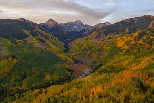 Aerial view of Capitol Peak and the snow capped Elk Range surrounded by vibrant autumn foliage in the Rocky Mountains near Snowmass Colorado United States. Aerial view of Capitol Peak and the snow capped Elk Range surrounded by vibrant autumn foliage in the Rocky Mountains near Snowmass Colorado United States.