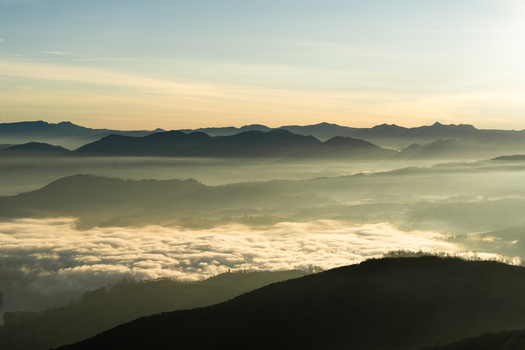 View of Adam s Peak surrounded by a thick sea of clouds and mountain silhouettes at sunrise in Ratnapura Sabaragamuwa Province Sri Lanka. View of Adam s Peak surrounded by a thick sea of clouds and mountain silhouettes at sunrise in Ratnapura Sabaragamuwa Province Sri Lanka.
