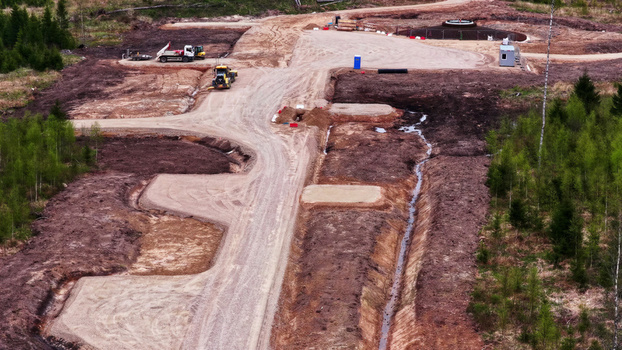 Aerial view of wind turbine foundation construction site with heavy machinery dirt access roads and drainage ditches surrounded by a dense forest in Latvia. Aerial view of wind turbine foundation construction site with heavy machinery dirt access roads and drainage ditches surrounded by a dense forest in Latvia.