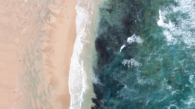 Aerial view of the sandy shoreline of Constantine Bay with turquoise ocean water and gentle waves breaking on the beach in Padstow Cornwall United Kingdom. Aerial view of the sandy shoreline of Constantine Bay with turquoise ocean water and gentle waves breaking on the beach in Padstow Cornwall United Kingdom.