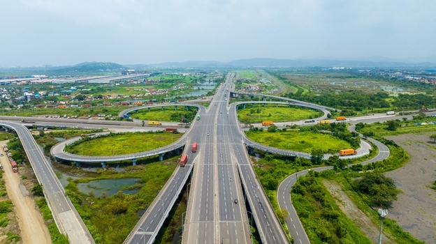 Aerial view of the Jawaharlal Nehru Port Authority highway interchange featuring multi level roads green surroundings and cargo trucks in Juna Sheva Maharashtra India. Aerial view of the Jawaharlal Nehru Port Authority highway interchange featuring multi level roads green surroundings and cargo trucks in Juna Sheva Maharashtra India.