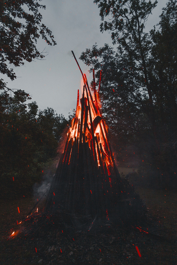 View of a large traditional bonfire burning brightly with glowing embers and sparks rising into the night sky in a forest setting in Laane County Estonia.