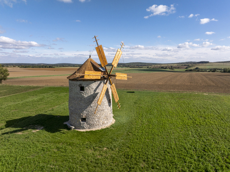 Aerial view of the historic Regi Szelmalom windmill standing in a green field surrounded by agricultural farmland under a blue sky in Tes Hungary. Aerial view of the historic Regi Szelmalom windmill standing in a green field surrounded by agricultural farmland under a blue sky in Tes Hungary.