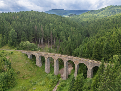 Aerial view of the Telgárt Viaduct a stone railway bridge with arches cutting through the dense green forest under a cloudy sky Telgárt Brezno District Slovakia. Aerial view of the Telgárt Viaduct a stone railway bridge with arches cutting through the dense green forest under a cloudy sky Telgárt Brezno District Slovakia.