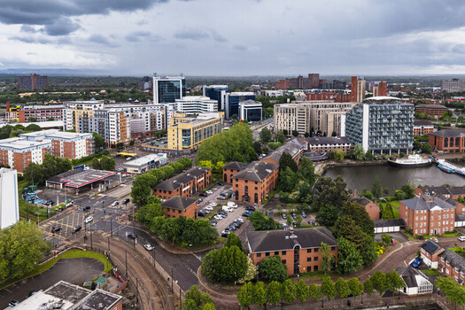 Aerial view of MediaCityUK featuring modern office buildings residential apartments and waterfront views under a cloudy sky in Salford England United Kingdom. Aerial view of MediaCityUK featuring modern office buildings residential apartments and waterfront views under a cloudy sky in Salford England United Kingdom.