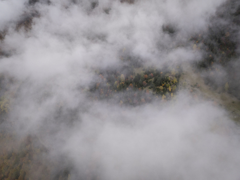 Aerial view of the Pyrenees mountains with dense forest and autumn foliage partially obscured by thick clouds in Spain. Aerial view of the Pyrenees mountains with dense forest and autumn foliage partially obscured by thick clouds in Spain.