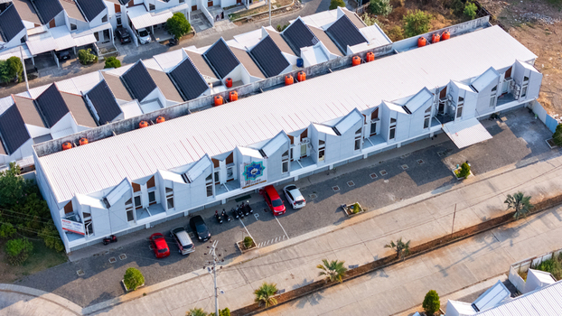 Aerial view of a modern residential complex featuring distinctive sawtooth roofs a parking area with parked cars and surrounding urban landscape in Semarang Central Java Indonesia. Aerial view of a modern residential complex featuring distinctive sawtooth roofs a parking area with parked cars and surrounding urban landscape in Semarang Central Java Indonesia.