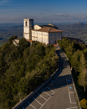 Aerial view of the Santuario del Santissimo Salvatore on a lush wooded hilltop with a winding access road under a clear sky in Montella Campania Italy. Aerial view of the Santuario del Santissimo Salvatore on a lush wooded hilltop with a winding access road under a clear sky in Montella Campania Italy.