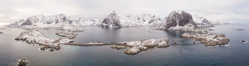 Aerial view of Lofoten islands with snow covered mountains rocky coastlines and bridges connecting small fishing villages surrounded by the sea in Nordland Norway.