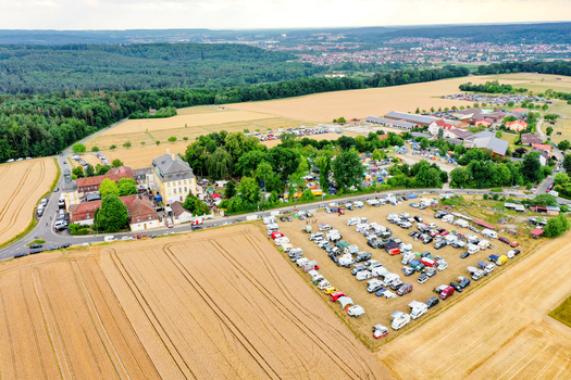 Aerial view of Schloss Jagersburg surrounded by golden fields and a large parking area with campers in Eggolsheim Bayern Germany. Aerial view of Schloss Jagersburg surrounded by golden fields and a large parking area with campers in Eggolsheim Bayern Germany.