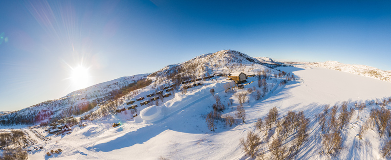 Aerial view of the snow covered landscape surrounding the Snowhotel with small cabins frozen terrain and bright sunlight in Kirkenes Finnmark Norway. Aerial view of the snow covered landscape surrounding the Snowhotel with small cabins frozen terrain and bright sunlight in Kirkenes Finnmark Norway.