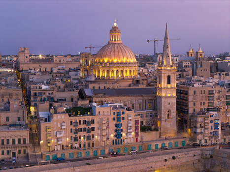 Aerial view of the illuminated dome and spire of St. Paul s Pro Cathedral rising above the historic limestone buildings of the old town at twilight in Valletta Port Region Malta. Aerial view of the illuminated dome and spire of St. Paul s Pro Cathedral rising above the historic limestone buildings of the old town at twilight in Valletta Port Region Malta.
