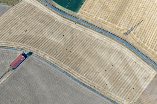 Aerial view of harvested agricultural fields with scattered hay bales a small building and a rural road in Hombourg Grand Est France. Aerial view of harvested agricultural fields with scattered hay bales a small building and a rural road in Hombourg Grand Est France.