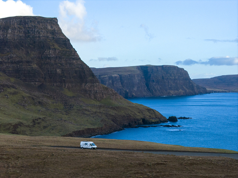 Aerial view of a white van driving on a road near the dramatic Neist Point cliffs and blue sea in Isle of Skye Scotland United Kingdom. Aerial view of a white van driving on a road near the dramatic Neist Point cliffs and blue sea in Isle of Skye Scotland United Kingdom.