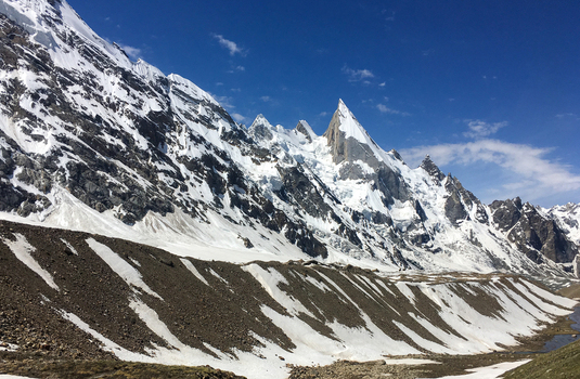 View of Laila Peak with its distinctive pyramid shape rising above snow covered glaciers and rocky slopes under a clear blue sky in Gilgit Pakistan. View of Laila Peak with its distinctive pyramid shape rising above snow covered glaciers and rocky slopes under a clear blue sky in Gilgit Pakistan.