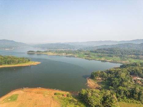 Aerial view of Wadaslintang Reservoir surrounded by lush green hills and forests with agricultural fields along the shoreline in Wadaslintang Central Java Indonesia. Aerial view of Wadaslintang Reservoir surrounded by lush green hills and forests with agricultural fields along the shoreline in Wadaslintang Central Java Indonesia.