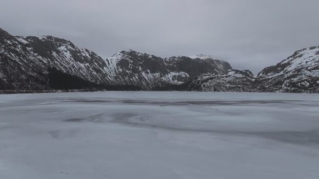 Aerial view of frozen lake and snowy mountains in Lofoten Norway.