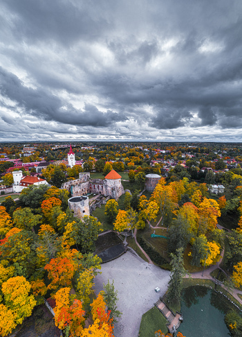 Aerial view of Cesis Castle surrounded by vibrant autumn trees historic stone ruins and a park with a pond under a dramatic cloudy sky in Cesis Cesis Municipality Latvia. Aerial view of Cesis Castle surrounded by vibrant autumn trees historic stone ruins and a park with a pond under a dramatic cloudy sky in Cesis Cesis Municipality Latvia.
