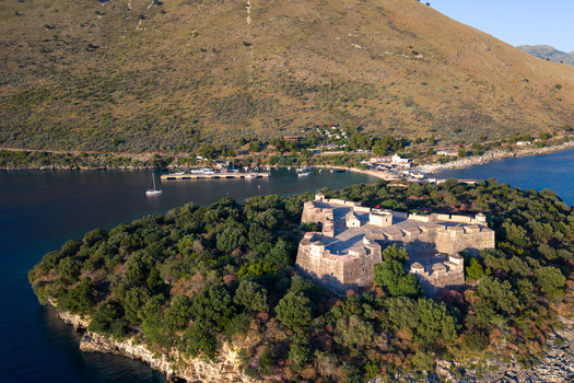 Aerial view of the historic Porto Palermo Castle on a green peninsula surrounded by the blue waters of the Ionian Sea in Porto Palermo Qarku i Vlores Albania. Aerial view of the historic Porto Palermo Castle on a green peninsula surrounded by the blue waters of the Ionian Sea in Porto Palermo Qarku i Vlores Albania.