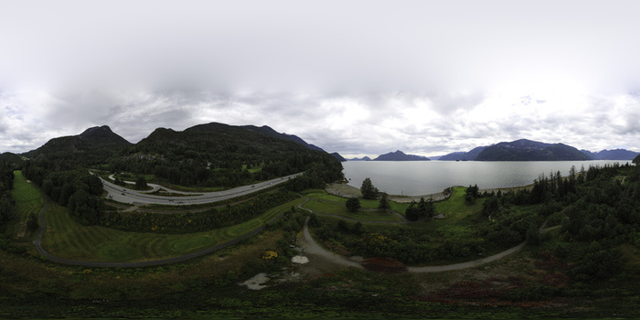 Aerial view of a coastal highway winding through lush forests and mountains along the water in Metro Vancouver A British Columbia Canada.