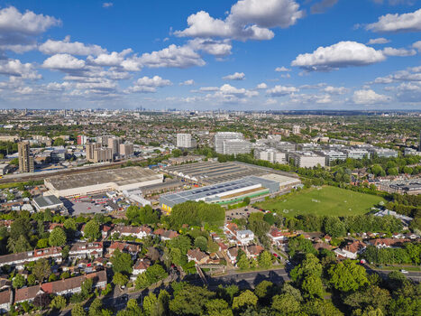 Aerial view of Brentford urban landscape featuring industrial buildings residential housing green spaces and a clear blue sky with scattered clouds in Brentford England United Kingdom. Aerial view of Brentford urban landscape featuring industrial buildings residential housing green spaces and a clear blue sky with scattered clouds in Brentford England United Kingdom.