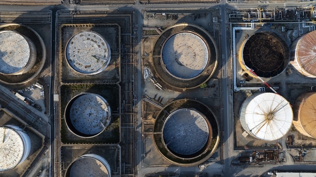 Aerial view of large circular industrial storage tanks and complex piping systems at an oil refinery in Cagliari Sardinia Italy. Aerial view of large circular industrial storage tanks and complex piping systems at an oil refinery in Cagliari Sardinia Italy.