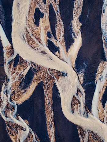Aerial view of braided river channels with sediment rich water flowing through dark volcanic sand in Iceland. Aerial view of braided river channels with sediment rich water flowing through dark volcanic sand in Iceland.